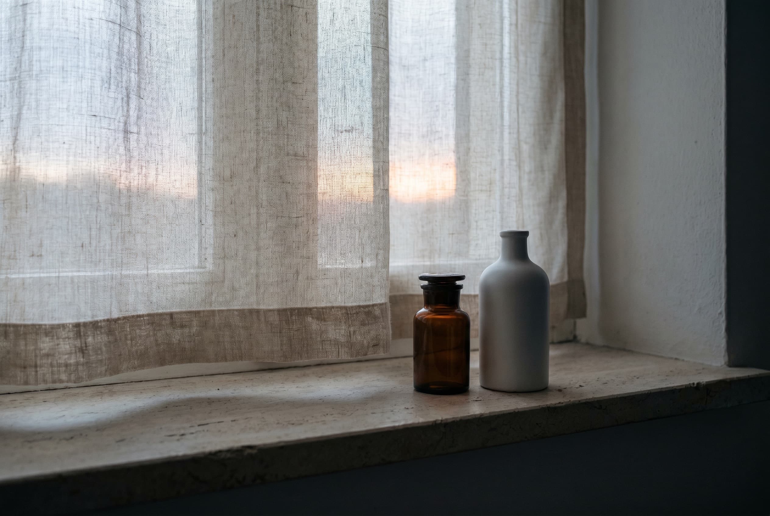 A single ceramic cup on a plaster windowsill in the first cool light of dawn.